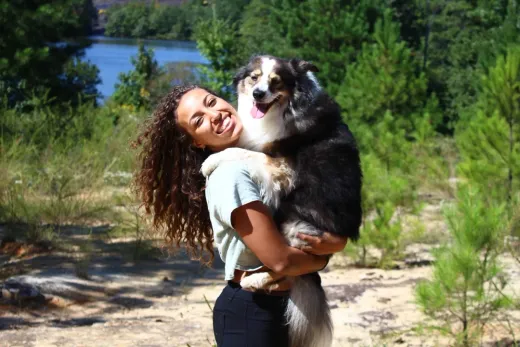 Emalee holding a happy Australian shepherd outdoors